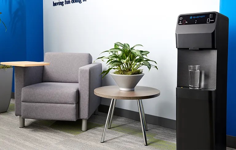 Q4 bottleless water cooler in office setting with plant next to it