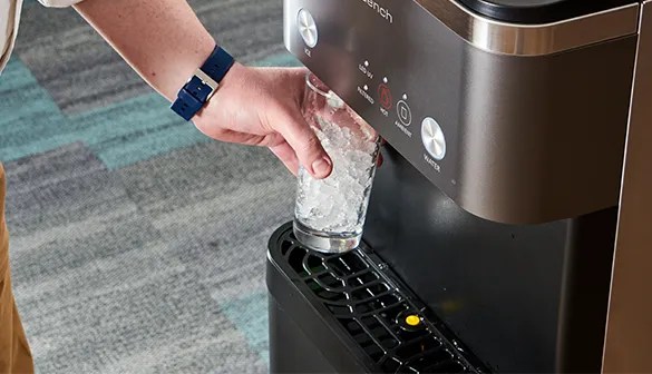 man dispensing chewable nugget ice from a water and ice dispenser in an office