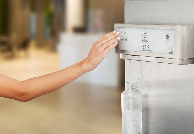 woman's hand with white nail polish dispensing vero water dispenser