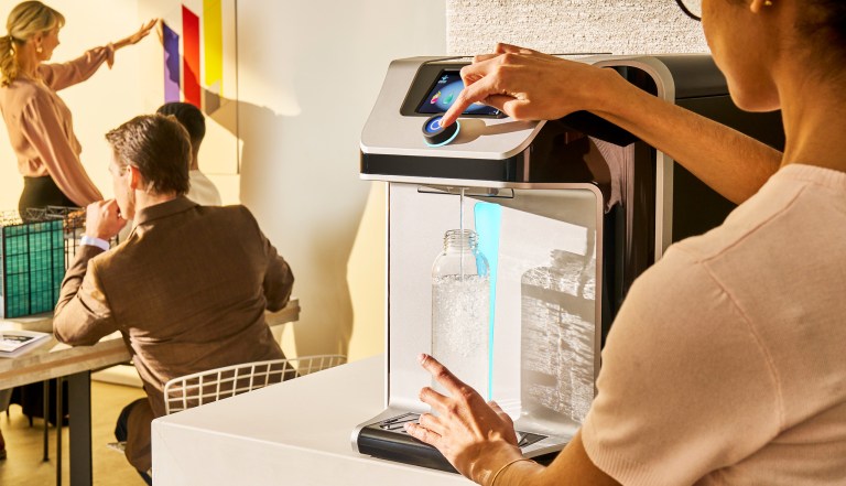 woman with glasses dispensing q10 sparkling water dispensing in office