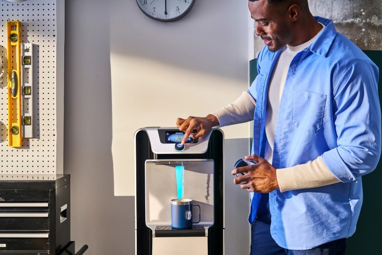 Man dispensing water from a Q10 bottleless water cooler in a workshop